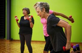 An image of three women using dumb bells to exercise indoors